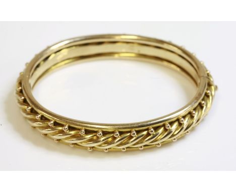 A late Victorian hinged gold bangle,with a central rope twist.  Applied gold beads to each side, with plain tubular guards to