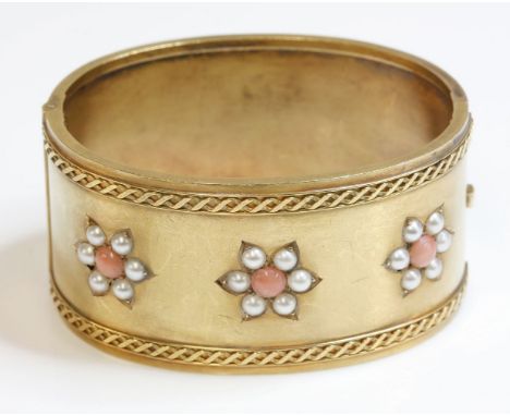 A Victorian coral and split pearl gold hinged bangle,a flat section hinged bangle, 32mm wide, with three flower head clusters