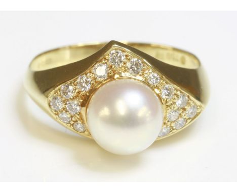 An 18ct gold cultured pearl and diamond ring, by Mikimoto,with a 7.9mm cultured pearl peg set to the centre.  A triangular su