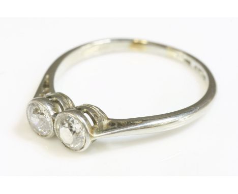 An Art Deco two stone diamond ring,with two old European cut diamonds, each one milligrain set in a plain collet to chenier s