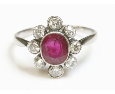 An Art Deco ruby and diamond oval cluster ring,with an oval mixed cut ruby, milligrain set in a plain collet.  A spaced borde