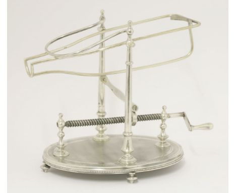 A Continental silver-plated wine cradle, late 19th century,on an engine turned oval base, on four baluster feet, with ratchet