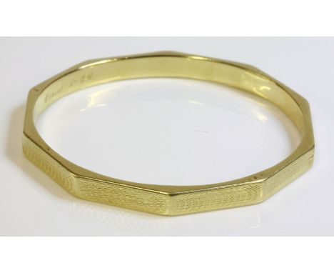 A 15ct gold Art Deco slave bangle of decagonal form,with flat section engine turned faces, hand engraved presentation inscrip