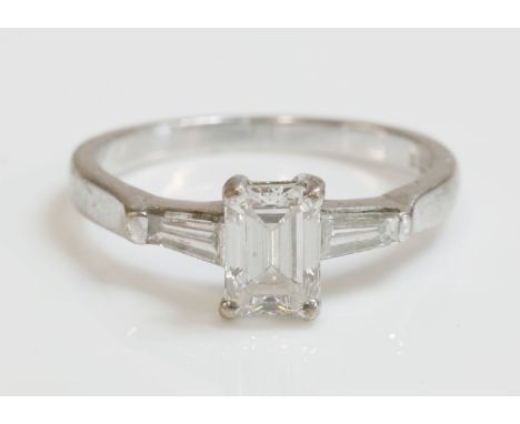 An 18ct white gold single stone diamond ring,with diamond set shoulders, an emerald cut diamond with an estimated weight of a