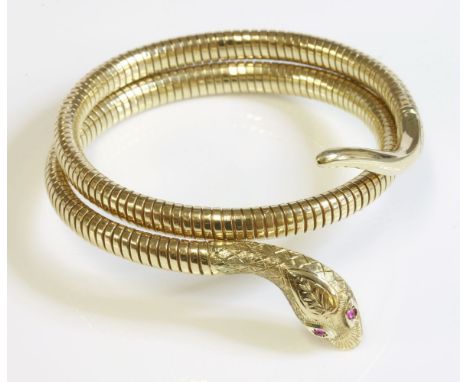 A 9ct gold coiled snake or serpent bangle by Cropp & Farr,with hand engraved head, cabochon ruby eyes and an interior steel s