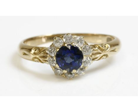 An Edwardian sapphire and diamond circular cluster ring,with a circular mixed cut sapphire, claw set to the centre.  A surrou