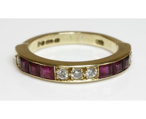 An 18ct gold diamond and ruby half eternity ring,with a central set of three brilliant cut diamonds, grain set in a row.  Set