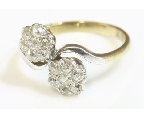 A double cluster diamond crossover ring, early 20th century,with old Swiss cut and old eight cut diamonds, claw set to two cl