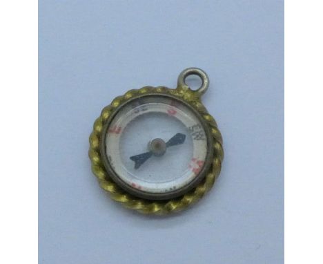 A yellow metal compass fob or charm