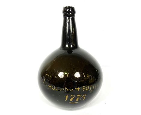 An 18th century onion shaped wine bottle, of typical form, with partly indistinct gilt lettering “Holding 4 Bottles, 1775”, 2