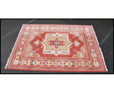 A good wool carpet on red ground having a tribal design dating to the 20th century. Measures 90inches x 67inches 