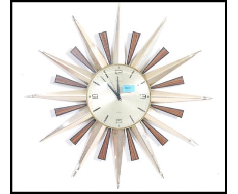 A vintage mid century sunburst retro wall clock with  teak and gilded metal rays with silvered dial having part baton numeral