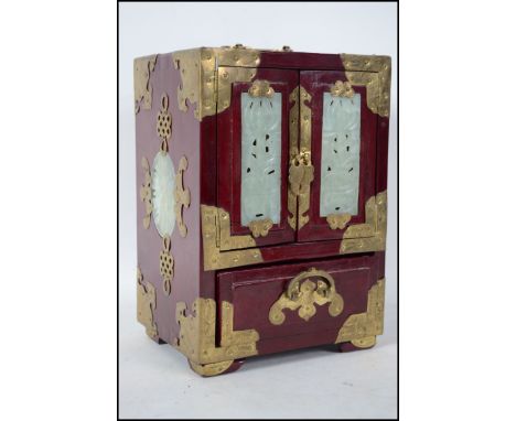 A 20th century Chinese hardwood laquered and jade adorned table top jewellery box having twin doors with drawers