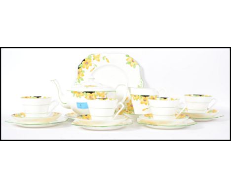 A 1930's Art Deco china tea service in the Clarice Cliff style having foliate design. The service complete with teapot and st