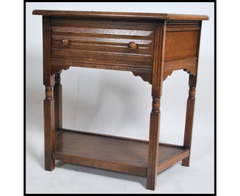 An Ercol oak console hall table being raised on turned legs with shaped cabinet top having reeded facia with single drawer to