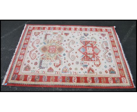 A good wool carpet on cream ground having a tribal design dating to the 20th century. Measures 88inches x 66inches