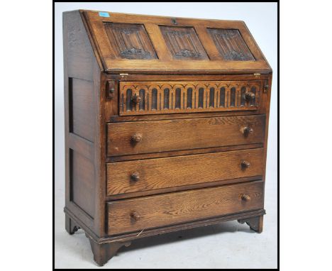 An Ercol Old Colonial / Jacobean revival oak and elm bureau having linen fold fall front writing slope over appointed interio