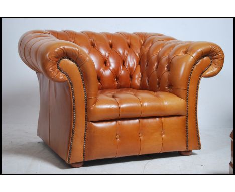 A good large Antique style tan brown leather Chesterfield club armchair having oversized barrel arms and back rests with butt