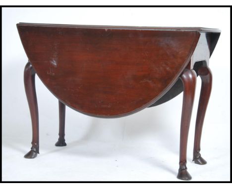 An 18th century Georgian mahogany drop leaf / gate leg dining table of oval form being raised on cabriole legs, each terminat