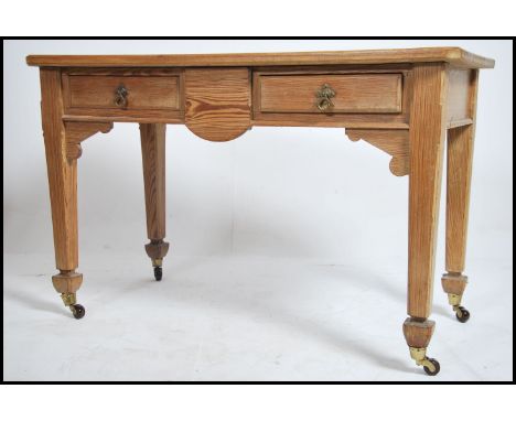 A Victorian pitch pine Arts & Crafts writing table desk. The heavy desk with square tapering legs having brown ceramic castor