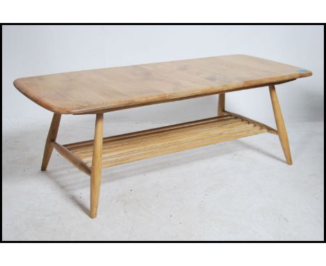 An Ercol light elm coffee table, rectangular form raised on splayed legs united with under tier magazine rack, 36 cms high, 1