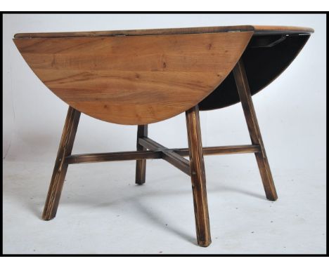 A retro Ercol drop leaf dining table being raised on squared legs with drop leaves being raised on fly supports. Marked for E