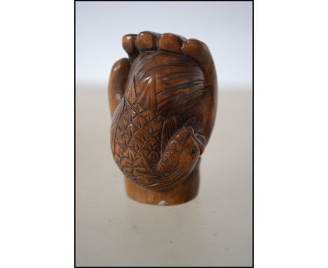 A Japanese carved wooden netsuke in the form of a fist signed to the edge