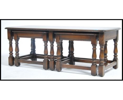 A 20th century  Ercol dark elm nest of long John tables in the Jacobean style all raised on block and turned legs united by s