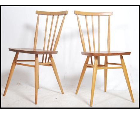 A good pair of 1970's Ercol beech and elm wood dining chairs raised on turned legs with peripheral stretchers  having saddle 