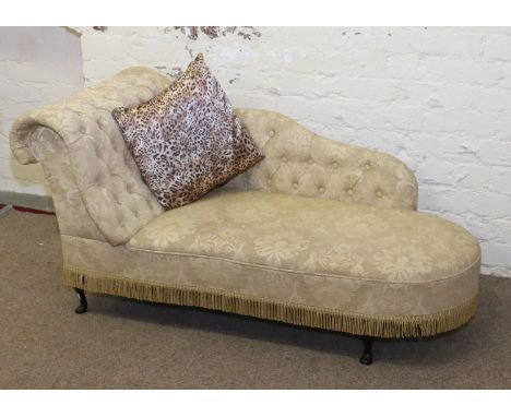 A deep buttoned gold upholstered chaise longue with four leopard print cushions.