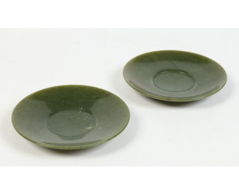 A pair of Chinese turned spinach jade saucers, 10cm diameter. Condition Report. To be used as a guide only. Good condition.