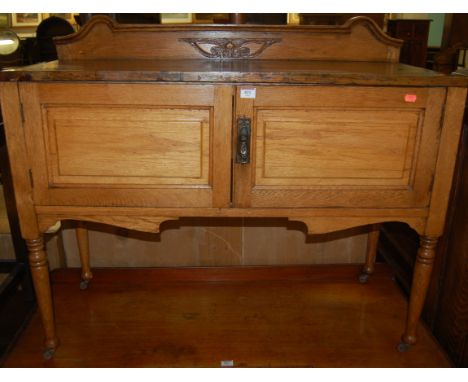 An Edwardian light oak and stained pine topped ledge back two door side cupboard