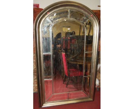 A large modern silvered and bevelled arch top over mantel mirror