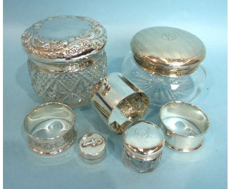 A cut-glass trinket pot with embossed silver lid, Birmingham 1896, another with engine-turned lid, three napkin rings and a p