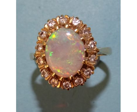 An opal and diamond cluster ring claw-set an oval opal within a border of fourteen 8/8-cut diamond points, in 18ct gold mount