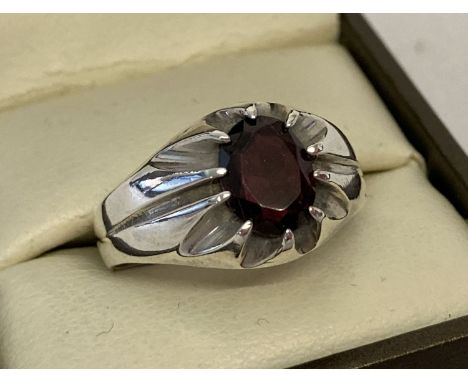 A men's vintage silver signet ring set with an oval cut garnet stone. Ring size U. Inside band marked SIL. 