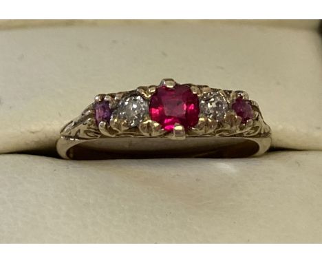 An 18kt gold vintage style ruby and diamond dress ring with scroll and floral design to mount. Central round cut ruby with a 