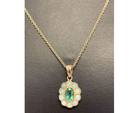 A 9ct gold emerald and opal set pendant on a 20 inch fine chain, by Luke Stockley, London. Central oval cut emerald surrounde