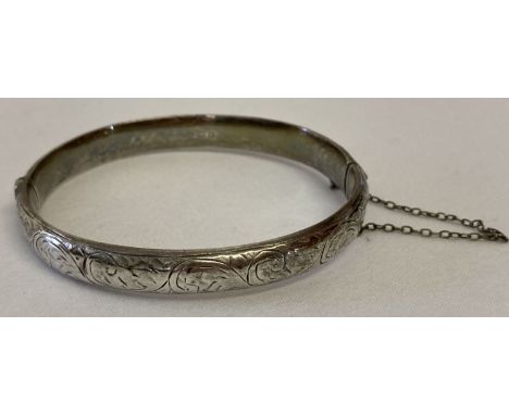 A vintage silver bangle with floral engraved decoration &amp; safety chain, hallmarked Birmingham 1954.  Total weight approx.