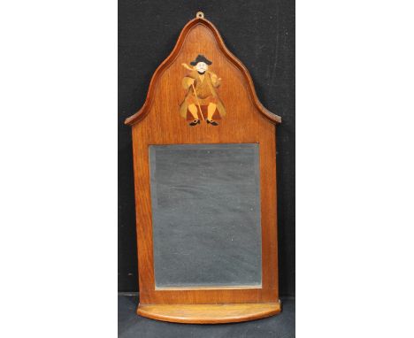 An Arts and Crafts oak wall mirror with shelf, inlaid with man smoking a churchwarden's pipe, bevelled plate, 69cm high 