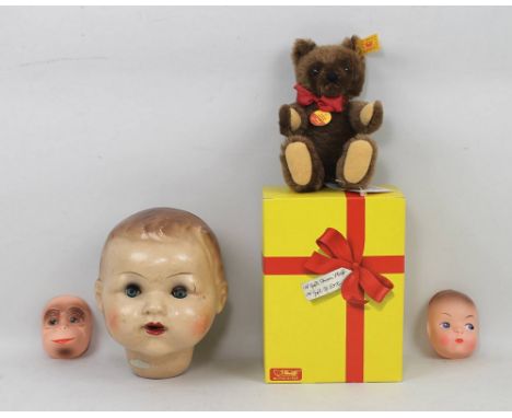 A Steiff teddy bear with original tags and box, no 0206/18, 19cm high, two doll's face masks, the one a baby doll with blue e