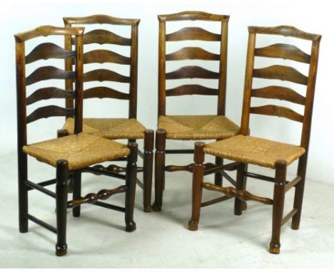 A set of four 19th century oak ladder back dining chairs with rush seats, raised on turned legs and pad feet, joined by turne