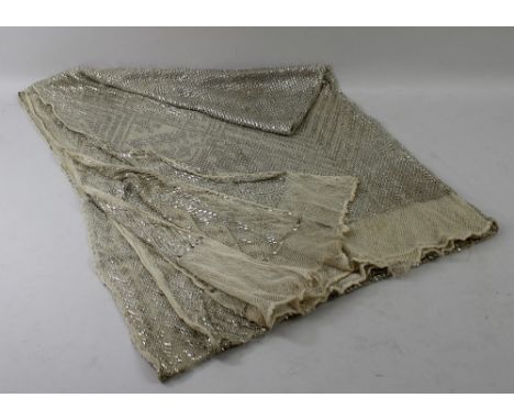 A vintage Assuit shawl, the cream knitted ground decorated with hammered silver coloured metal in geometric patterns and moti