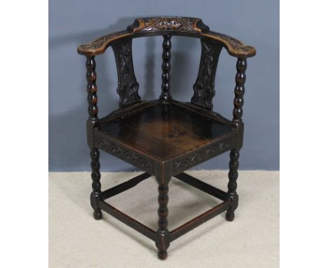 A Victorian oak Carolean style corner chair, with a solid seat, bobbin turned legs, stretchers and carved splats, 71 by 64 by