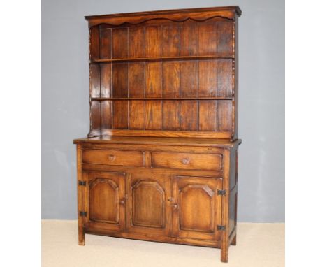 An oak kitchen dresser with a three shelf Delft rack above two drawers and three cupboard doors raised on square legs, 123 by