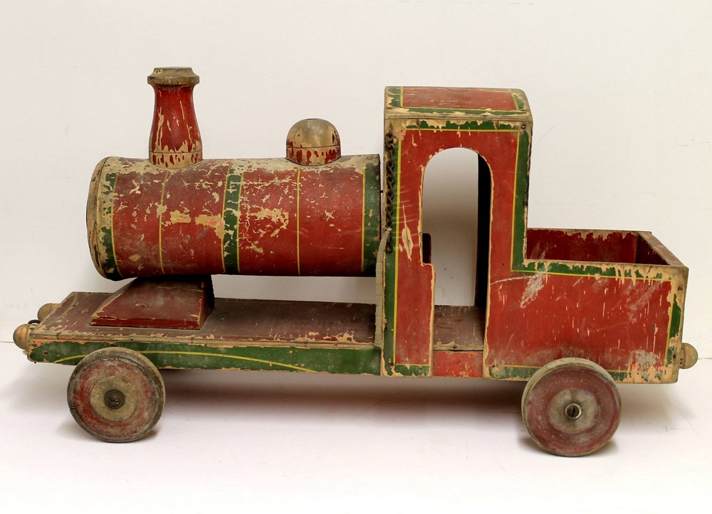 A vintage pull along wooden toy train painted in red and green livery, metal cap to cylinder end