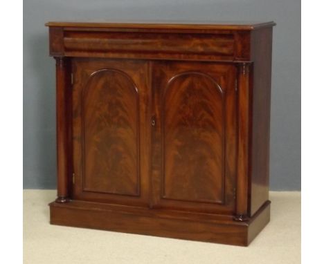 A Victorian mahogany chiffonier with a cushion drawer above a pair of doors flanked by turned columns, raised on a plinth bas