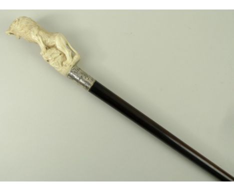 An ebony walking stick, early 20th century, the antler handle carved with a lion perched on a rock, silver ferrule monogram e
