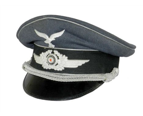 A German Third Reich Luftwaffe Officer’s Visor cap by Wilhelm Holters constructed of dark-grey wool with a woven black centre