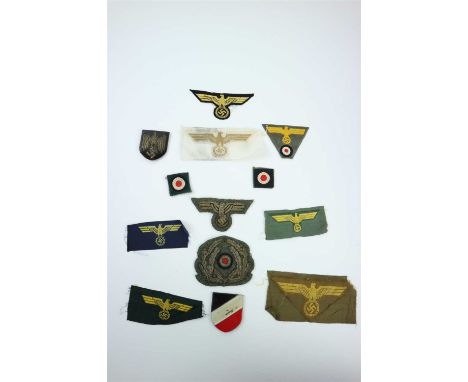 A grouping of German Third Reich Naval insignia including two cloth Kriegsmarine cap eagles and cockades, an embroidered Krie